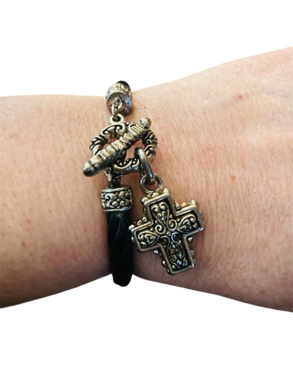 Silver-toned cross pendant paired with a cord bracelet featuring a toggle clasp